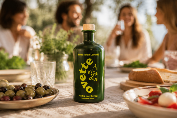 Ovette Extra Virgin Olive Oil on a Mediterranean table with fresh food and friends gathered in the background.